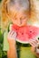 little blond girl eating a piece of watermelon portrait on nature