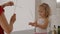 Little blond girl and female babysitter playing with wooden skewers in bathroom.