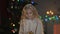 Little blond girl holding present under Christmas tree, magic winter atmosphere