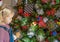 Little blond girl looking at decorated Christmas tree