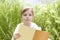 Little blond girl reading book green spikes garden