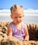 Little Blond Girl Sits in Sand Hole Plays on Beach