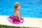 Little blond girl sitting smiling swimming pool