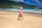 Little Blond Girl in Spotty Dress Runs by Wave Surf along Beach