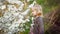 Little blond girl in thickets of blooming bushes.