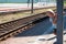 A little blond-haired boy of three years in a T-shirt and shorts on the platform is waiting for the train and playing