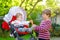 Little blond kid boy giving a carrot to baby sister. Happy siblings eating healthy snack. Baby girl sitting in pram or