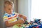 Little blond kid boy playing with lots of colorful plastic block