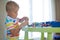 Little blond kid boy playing with lots of colorful plastic block