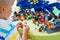 Little blond kid boy playing with lots of colorful plastic block