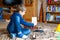 Little blond preschool kid boy playing with toy ship indoors