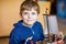 Little blond preschool kid boy playing with toy ship indoors