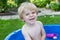 Little blond toddler boy playing with water in summer