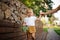 Little blonde brown-eyed girl holding a tree leaf and walking on the street holding mother hand