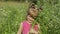 Little blonde child girl in pink dress stay on flower chamomile grass meadow. Bouquet of daisies