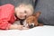 Little blonde curly girl hugging a red basenji dog.