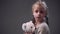 Little blonde European girl with braids hairstyle in a beige sweater holds white teddy bear, then looks towards the