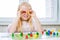 little blonde girl have fun, laugh and indulge playing board game. Hold people figures in hands like her eyes. yellow, blue, green