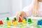 little blonde girl hold red people figure in hand. yellow, blue, green wood chips in children play - Board game and kids leisure c