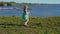 Little blonde girl inflates large soap bubbles against backdrop of sea coast.