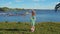 Little blonde girl inflates large soap bubbles against backdrop of sea coast.