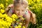 Little blonde girl inhales scent of flowers