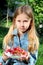 Little blonde girl with a plate of fresh strawberries in summertime