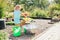 Little blonde girl playing at garden with water in a tin basin. Kids gardening. Summer outdoor water fun. Childhood in the country