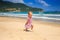 Little Blonde Girl in Spotty Dress Jumps on Sea Beach