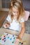 Little blonde girl in a white tshirt playing with plastic multicolor mosaic at home or preschool. Early education concept