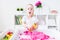 Little blonde girl wtih surprised face playing with pink kinetic sand on a white table in a light room. Sensory development