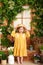 Little blonde girl in a yellow dress smiles and holds on to straw hat. Concept of childhood. Gardening. portrait of a beautiful ki