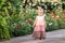 Little blue-eyed girl walks in a blooming garden in summer in long vintage linen dress