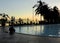 Little blurred view umbrella, chair, pool and beach with black silhouettes palm tree at sunrise times or sunset - vacation and