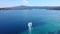 Little boat sailing on blue azure lagoon with transparent sea and islands. Aerial view