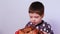 A little boy 3-4 years old holds a dish with rabbit meat  sniffs and swells.