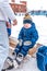 Little boy 3-5 years old, sitting on a bench for shoes, in the winter in a city park on a snow-covered skating rink. In