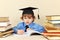 Little boy in academic hat writing pen in notebook among the old books