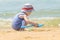 Little boy alone playing on the sea beach with sand