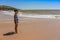 Little boy on anjuna beach with yellow sand, blue ocean and waves. North Goa, India. March 12, 2020.