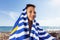 The little boy on the beach caped with a Striped blue and white beach towel and smiling happily
