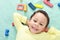 Little boy on the bed with various toy blocks and shapes