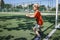 Little boy in black and orange soccer form playing football on open field in yard, young goalkeeper