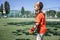 Little boy in black and orange soccer form playing football on open field in yard, young goalkeeper