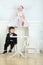 Little boy in black suit sitting on chair and girl