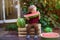 A little boy with blond hair n the summer on a sunny day sitting at a gazebo with a green grapes and eating a watermelon