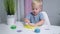 little boy blond playing with yellow shiny slime at the table at home