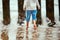 Little boy in blue pants running on sea coast and playing with sea waves, defocused blurred legs