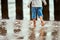Little boy in blue pants running on sea coast and playing with sea waves, defocused blurred legs