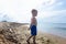 A little boy in blue shorts walks on a sandy seashore on a sunny day. Leisure, active lifestyle and travel